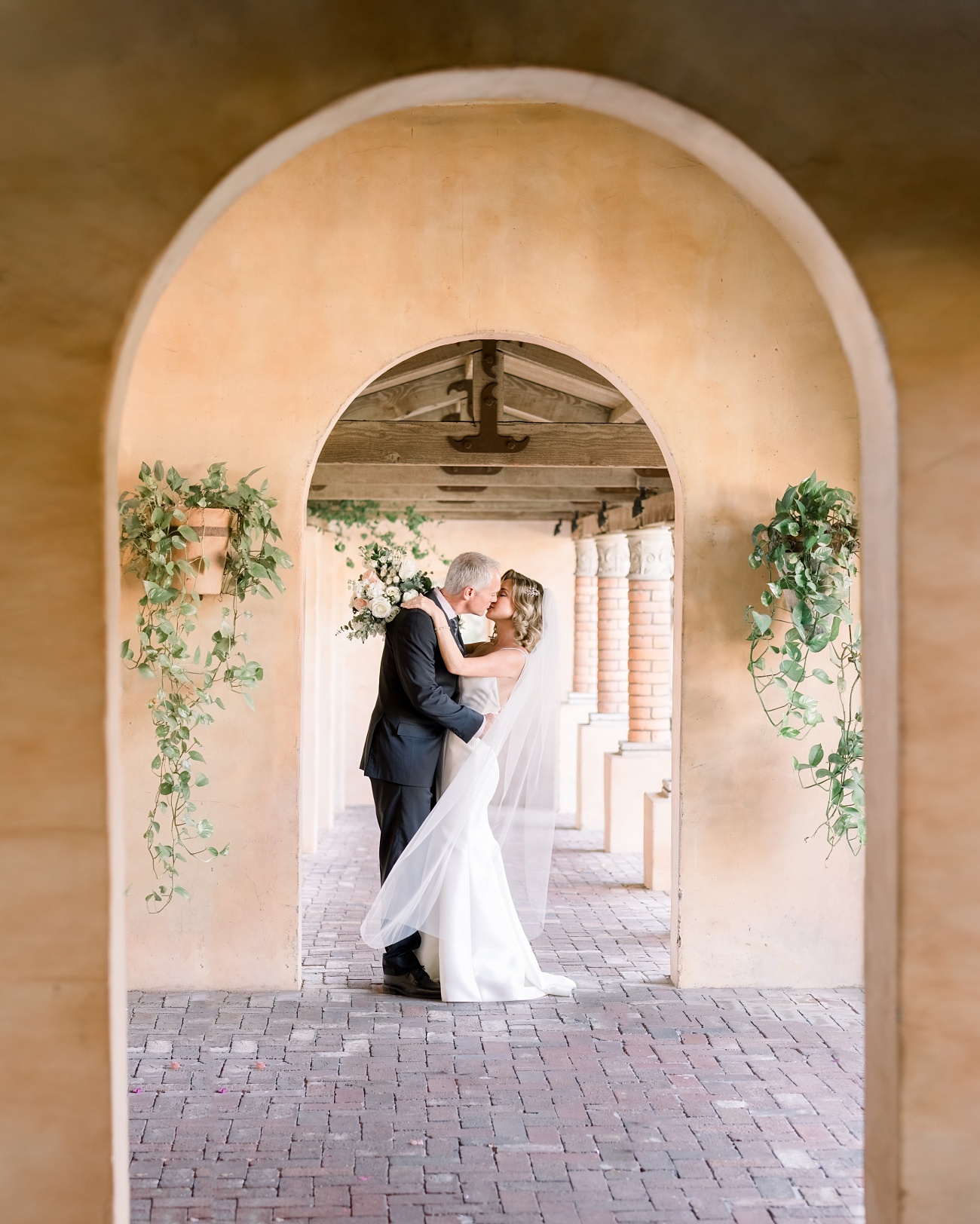 Soft image of bridal couple kissing under an arch at the Royal Palms Resort and Spa